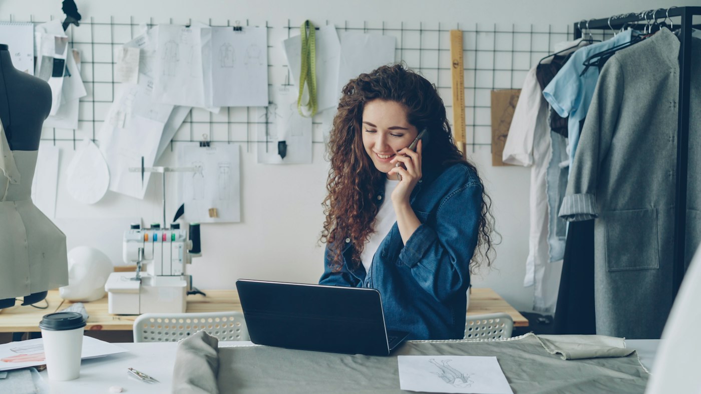 A business owner working on a laptop while on the phone